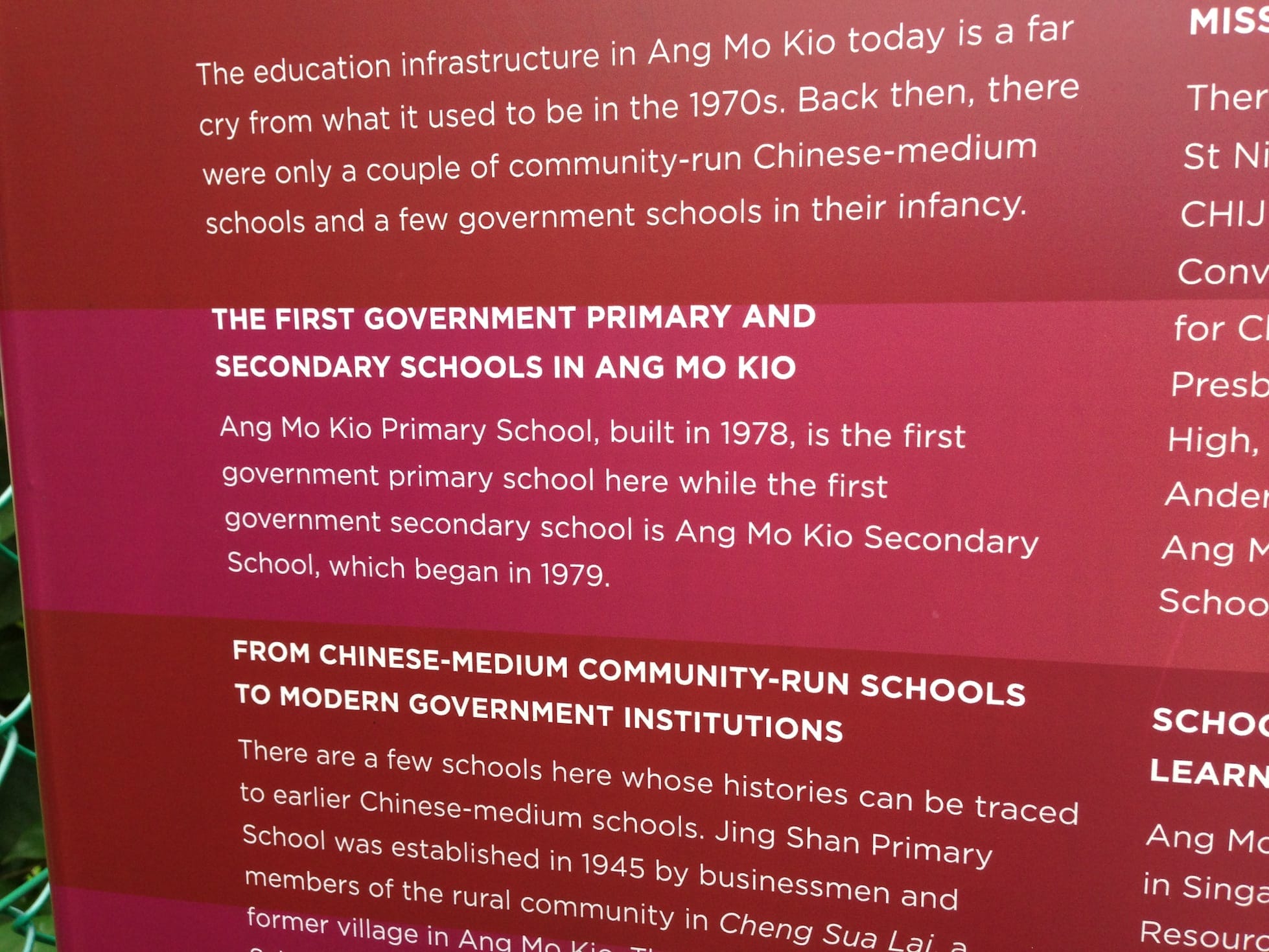 Red informational board about education history in Ang Mo Kio, Singapore, with white text on schools from 1970s onward.
